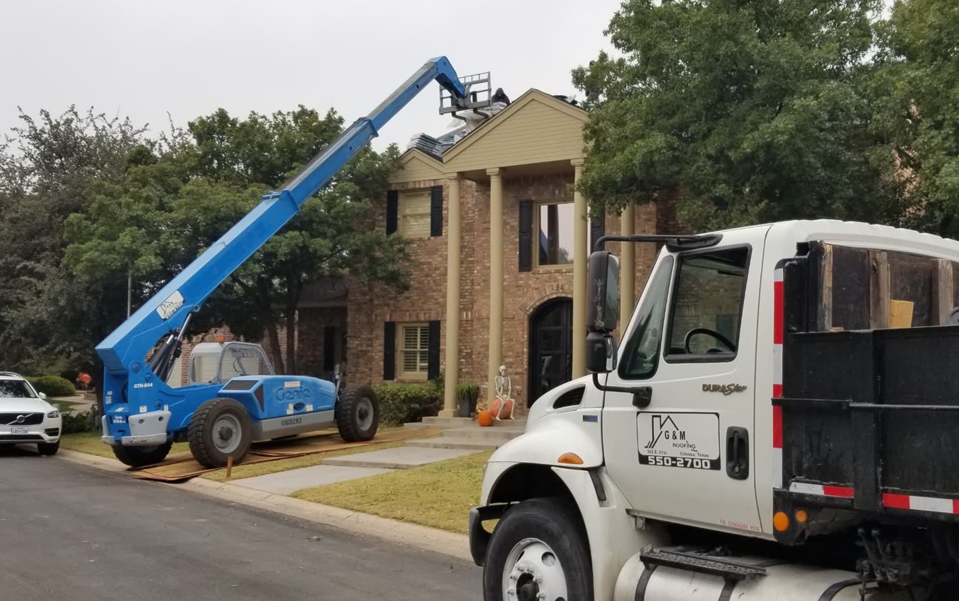 A G&M truck and a lift outside a two-story house during a reroof.